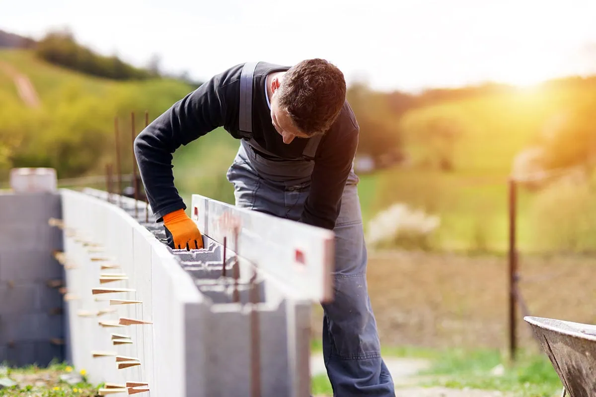 a bricklayer positions bricks in a wall.