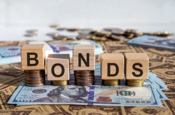 wooden blocks spelling bonds laid atop coins and cash.