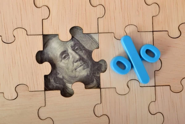 concept art of a puzzle piece removed revealing part of a dollar bill and a percent sign sits atop the puzzle indicating yield.