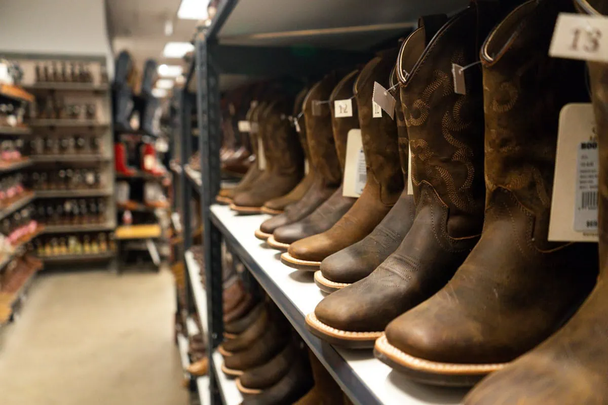 10 Best 'Rebound' Stocks to Buy for the Rest of 2026 6 Rows of boots at a Boot Barn store.