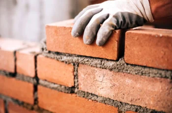 a bricklayer sets a brick into mortar.