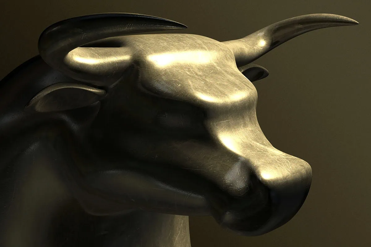 A closeup of a bronze casting depicting a stylized bull in contrasting light on an isolated dark background.