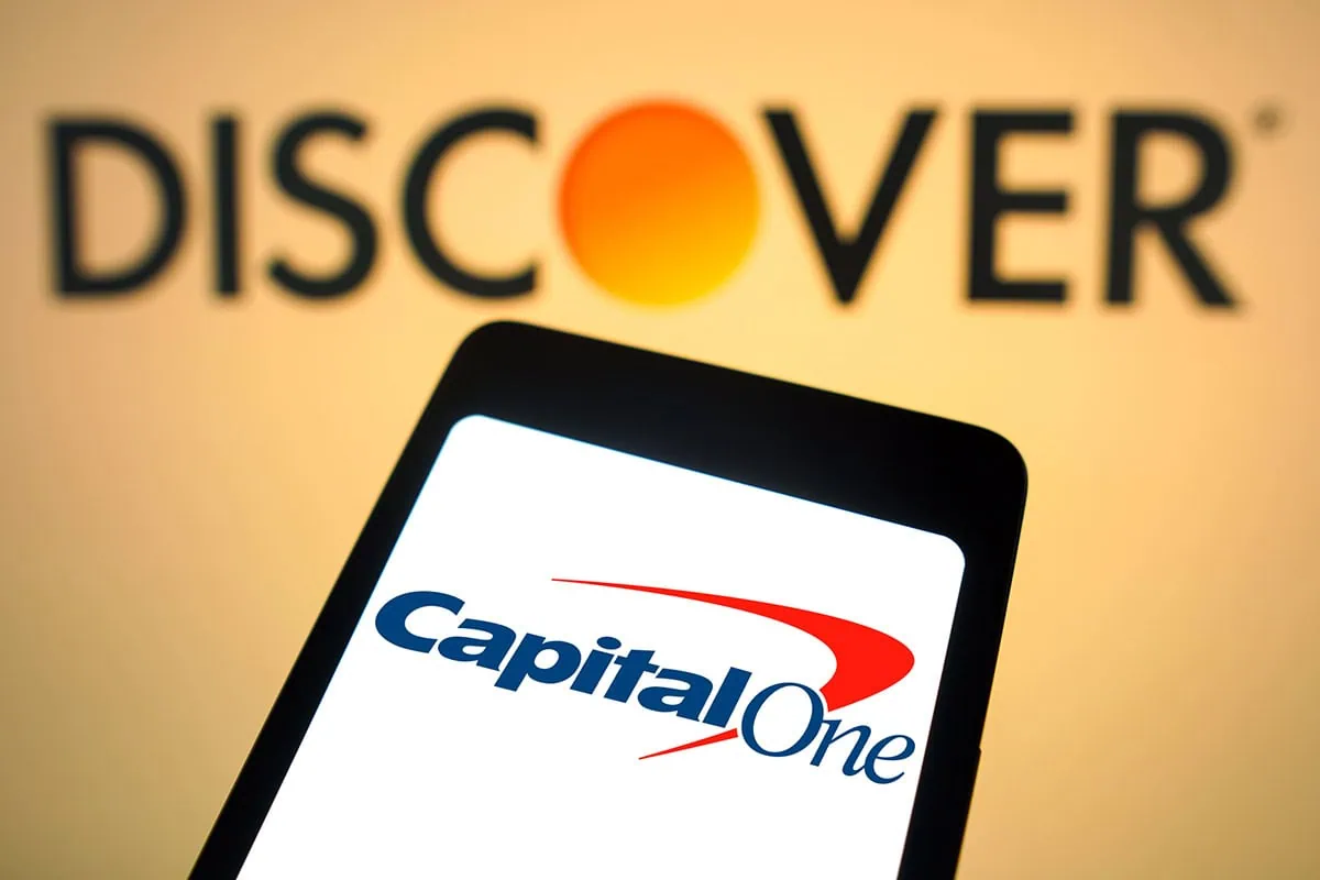7 Great Growth Stocks to Buy at 2025's Midpoint 5 the discover logo is shown above a phone displaying the capital one logo representing a merger between the two companies.
