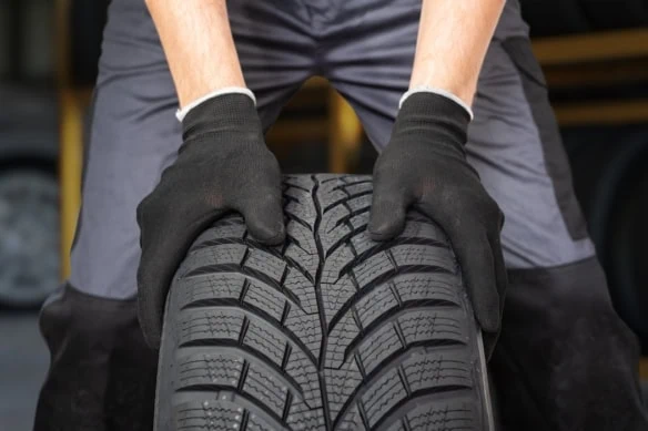 Car mechanic is preparing tire for change in garage.