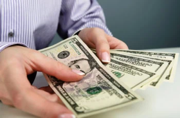 a person shuffles through five and hundred dollar bills.