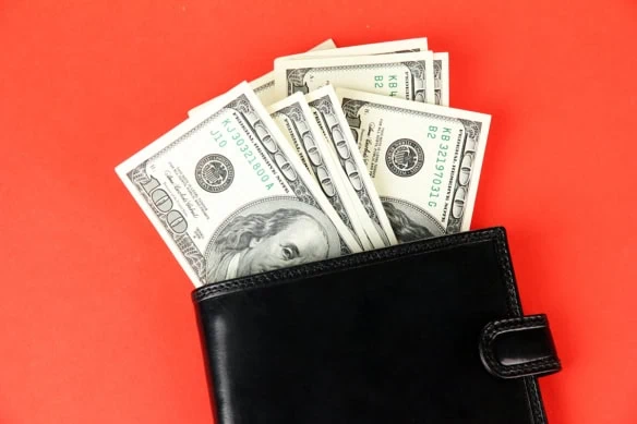 hundred dollar bills coming out of a wallet.