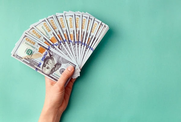 a person holding a spread-out fan of hundred dollar bills.