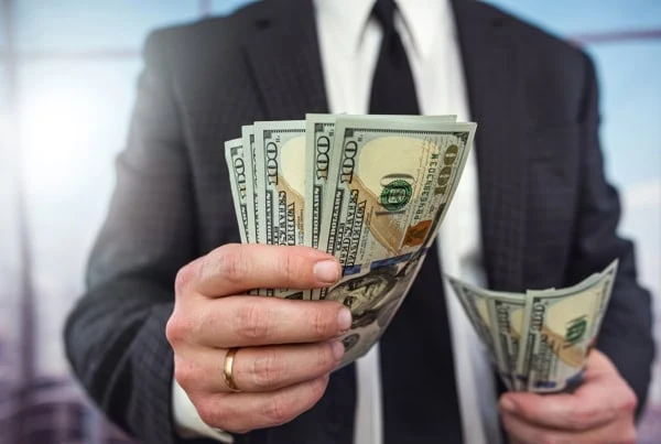 a businessman hands over several hundred dollars.