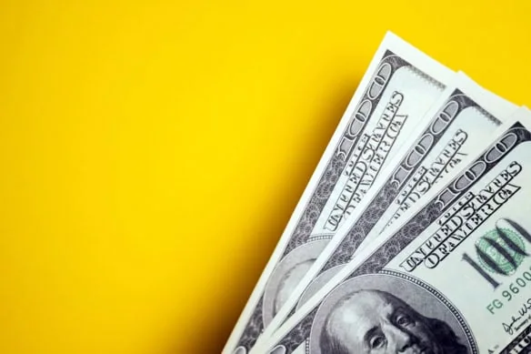 three hundred-dollar bills in front of a yellow background.
