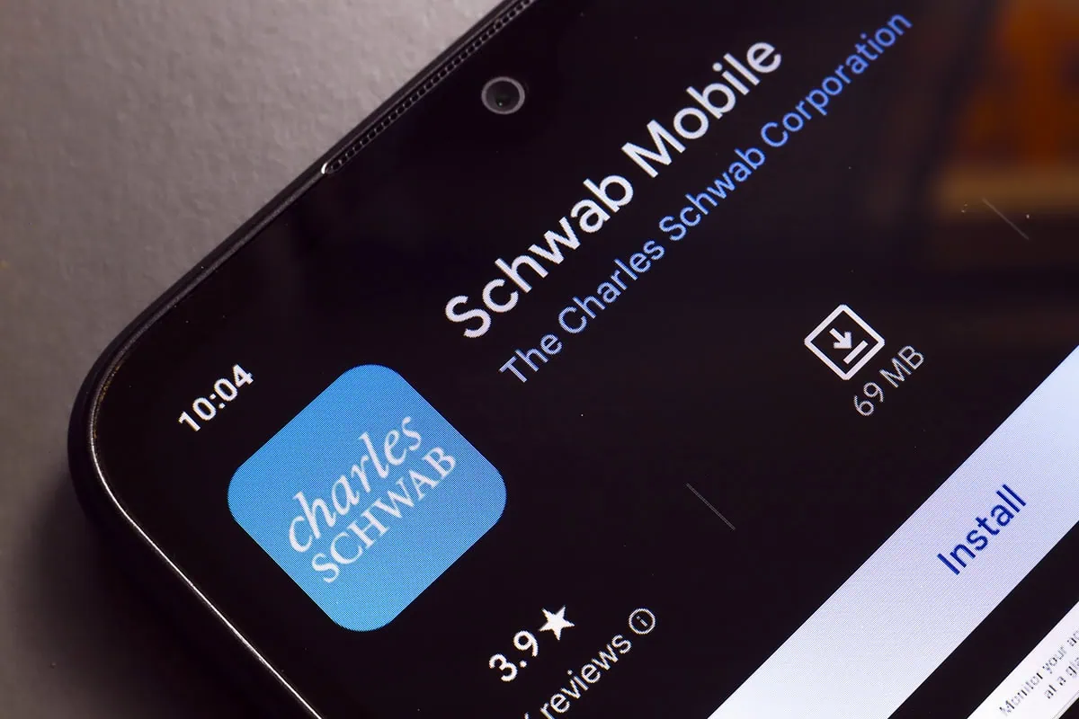Hands-off investing: Schwab Target-Date Funds Do the Work for You 11 the Charles Schwab Mobile app logo is displayed on a smartphone screen.