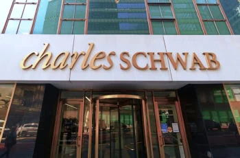 a gold charles schwab sign against a white background on a city building.