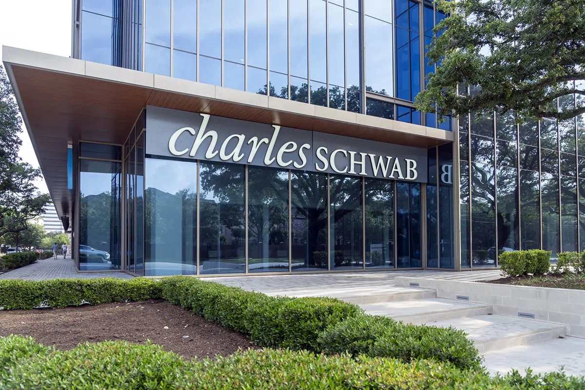 8 Best Schwab Funds for Retirement Savers 2 a glass building with a large charles schwab sign in a lush office park.