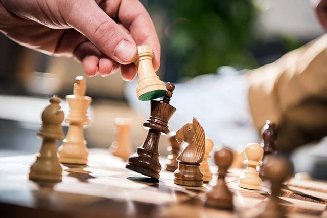 a person knocking out a king with a pawn in a game of chess.
