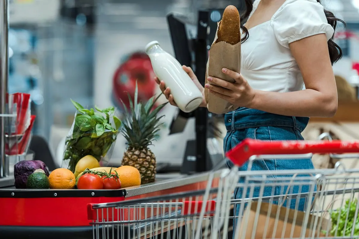 Build a Grocery-Store Defense With These Consumer Staples ETFs 4 a person checks out at the grocery counter.