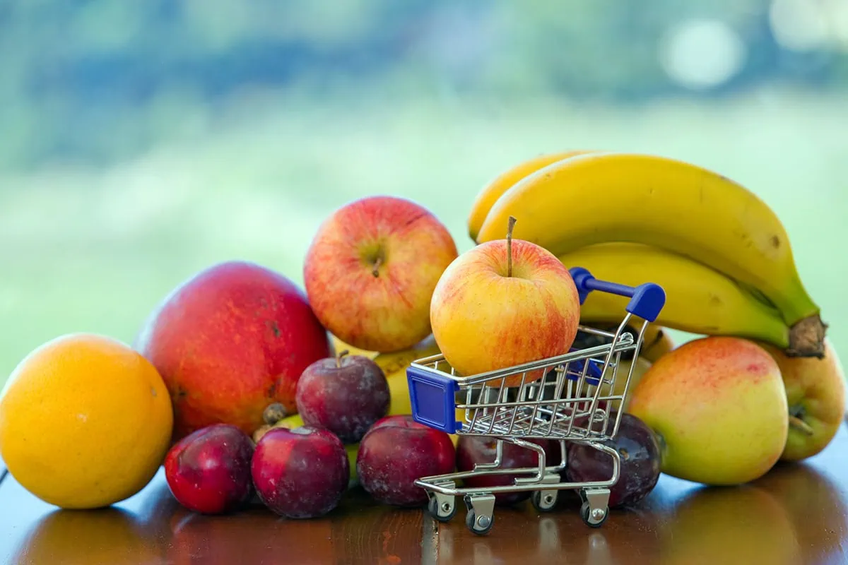 4 Best Consumer Staples ETFs You Can Buy 2 several different fruits, including a single apple filling up a tiny shopping cart.