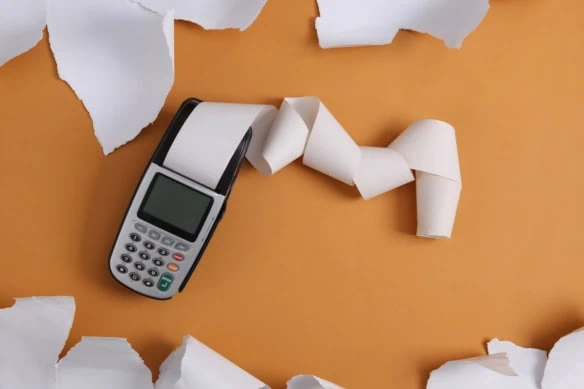 Payment terminal and white torn paper sheets on beige background