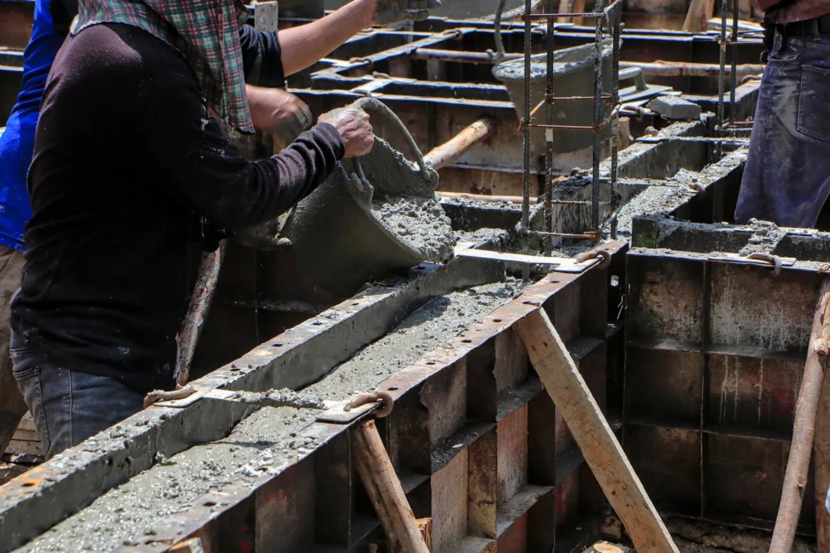 10 Best 'Rebound' Stocks to Buy for the Rest of 2026 4 Workers gathering concrete at a construction site.