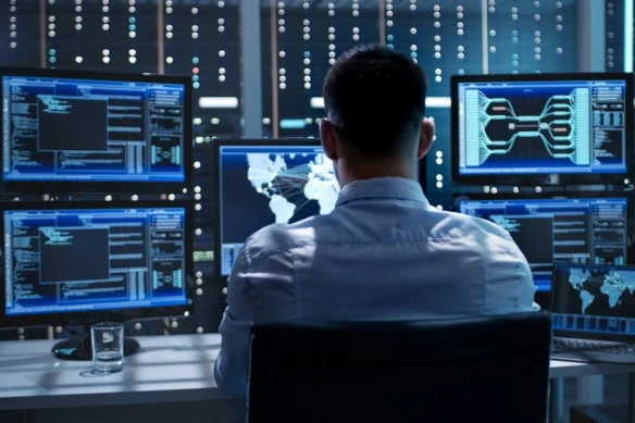 a cybersecurity expert monitors many different computer screens.