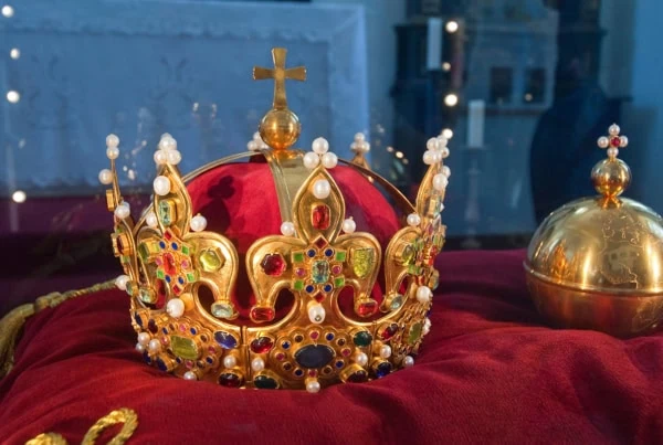 an ornate crown sits on a red velvet sheet.