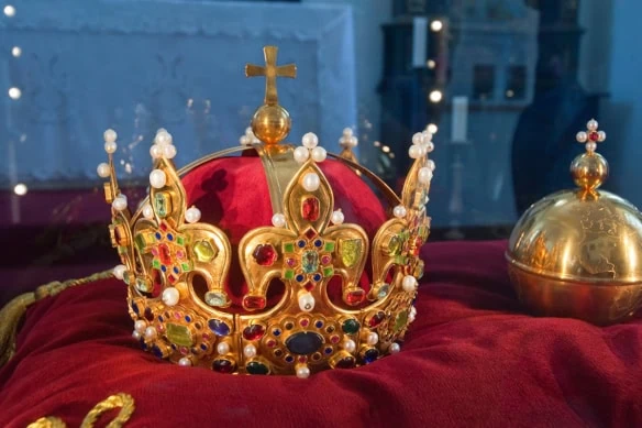 an ornate crown sits on a red velvet sheet.