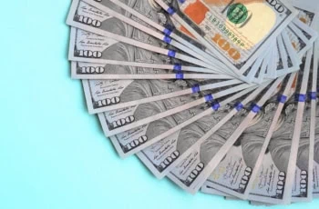 a fan of hundred dollar bills against a blue background.