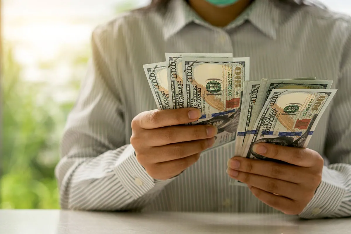 ๐ฏ Need a Benjamin? 12 Hyper-Fast Ways to Fill Your Bank Account 12 a person counts many hundred dollar bills.