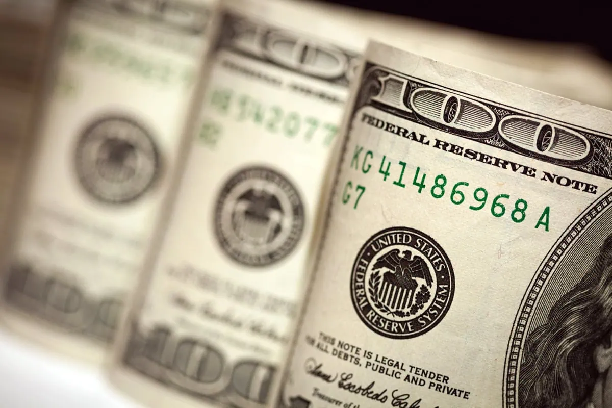 three rolls of hundred dollar bills side by side.