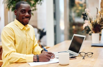 Young professional African American male sitting at a desk with a laptop.