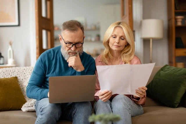 elderly couple looking at financial statements and computer problem solving