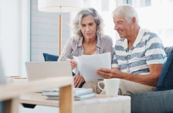 Seeing positive returns on their pension fund. a senior couple going through paperwork on the sofa at home.