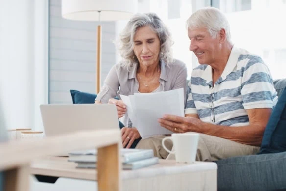 Seeing positive returns on their pension fund. a senior couple going through paperwork on the sofa at home.