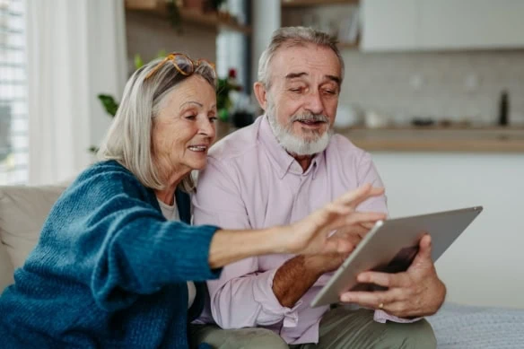 Senior couple scrolling tablet in their living room