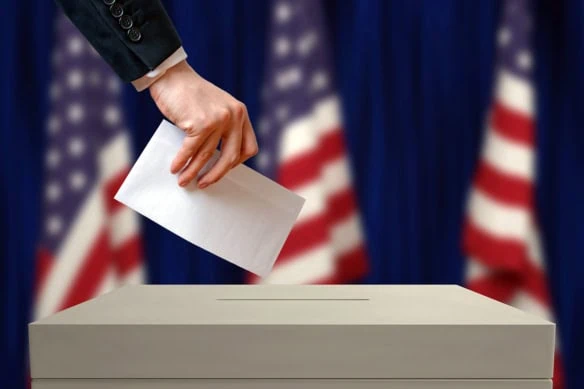 a woman places a vote into a ballot box.