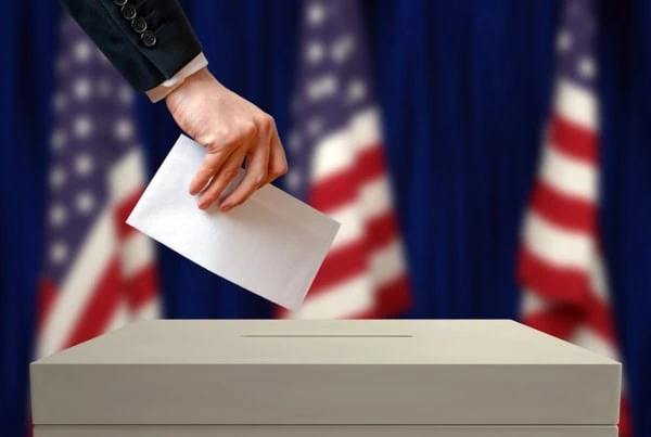 a woman places a vote into a ballot box.