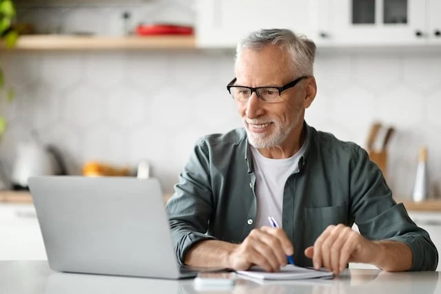 excited senior sitting at laptop and counter