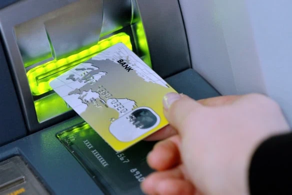 a person puts a debit card into an ATM.