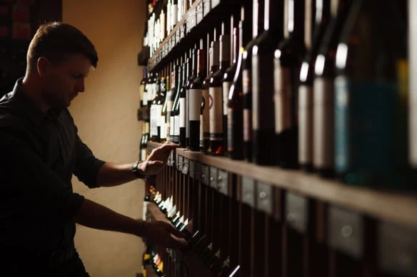 a sommelier looks for a bottle of wine.