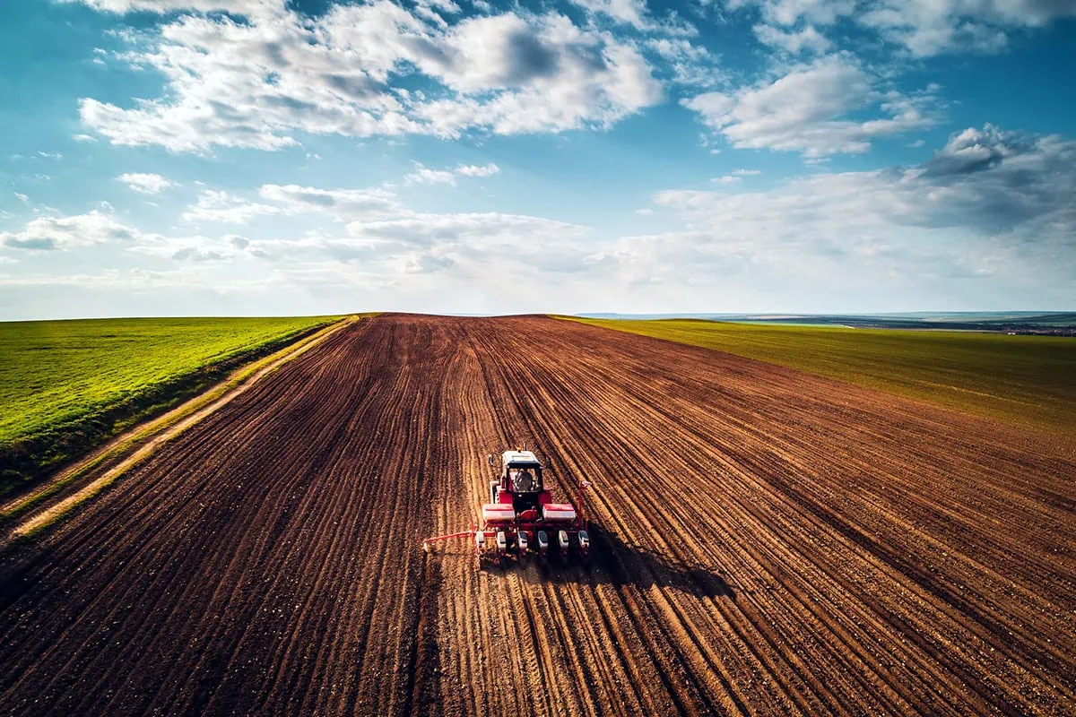 a red tractor going over farmland.
