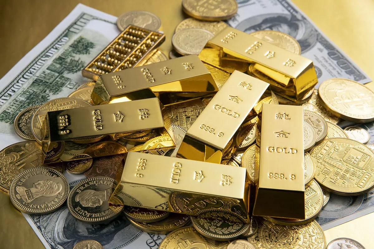 These 7 ETFs Will Fly If 2026's Gold Rally Continues 2 a pile of small gold bars and regular size gold coins sits on many dollar bills.