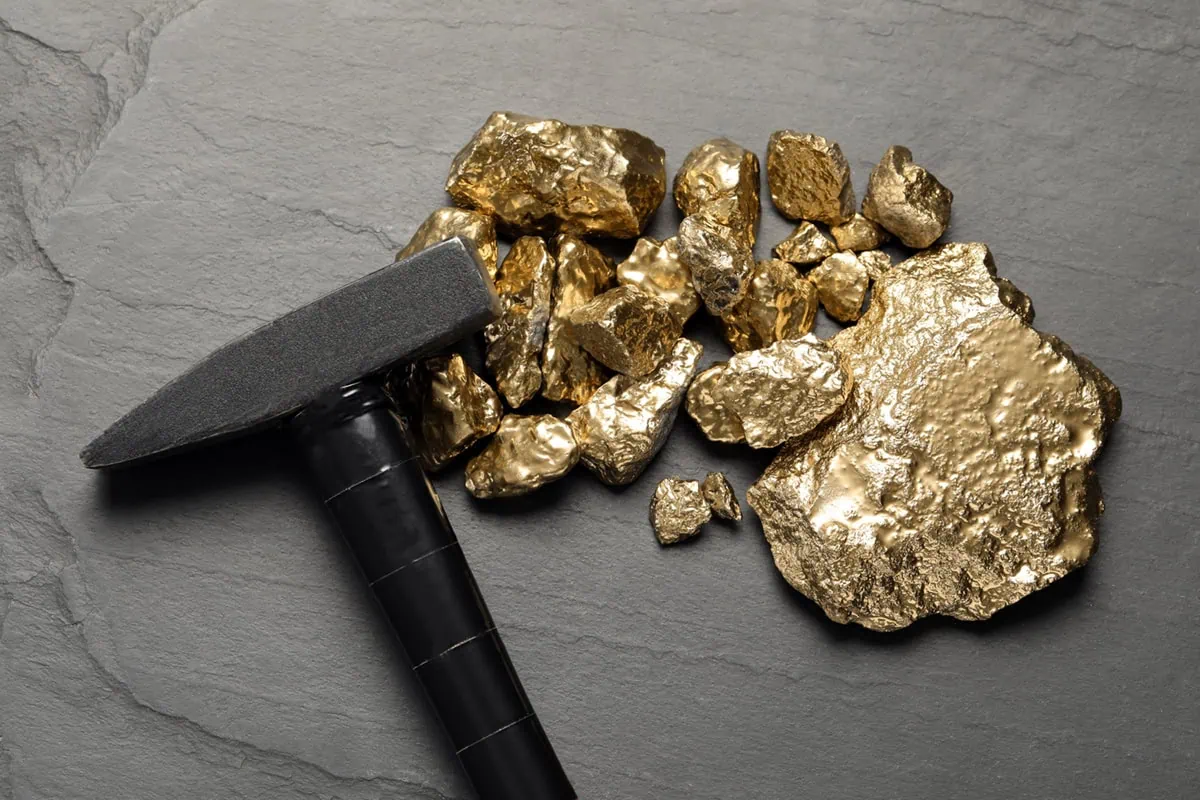 These 7 Gold ETFs Are Soaring as Gold Eclipses $4,000 8 gold nuggets and a mining hammer sit on a table.