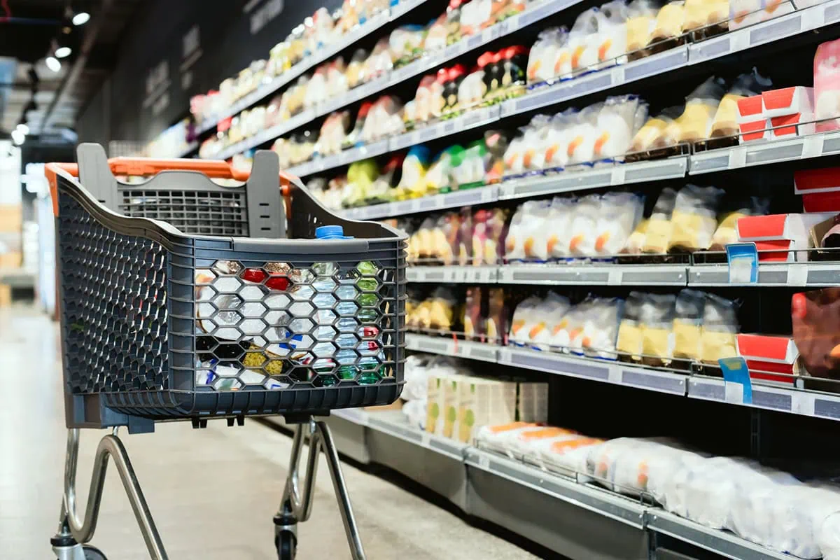 These 3 Consumer Staples Funds Deliver Safety and Income 4 a gray grocery cart sits near a cold-foods aisle.