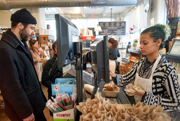 A grocery store worker helps a customer check out.