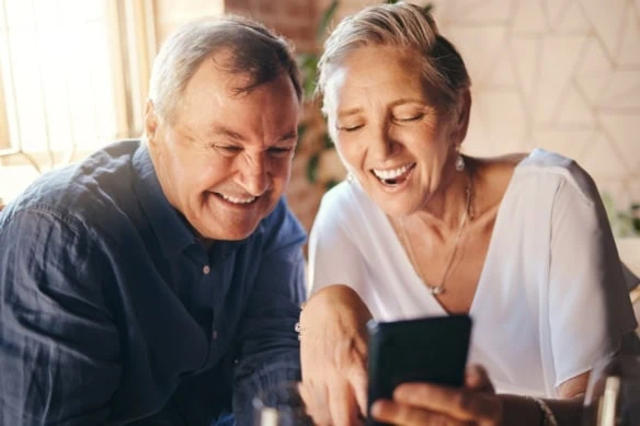 Happy, love and senior couple on a phone scrolling on social media together in coffee shop. Happiness, smile and elderly man and woman reading a blog on website or browsing the internet on smartphone