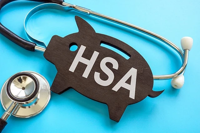 a stethoscope wrapped around a flat wooden piggy bank carving that says H S A.
