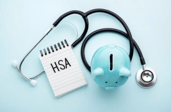 a piggy bank a stethoscope and a tablet that says H S A which stands for health savings account.