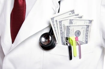 a doctor wears a lab coat that has pens and several hundred dollar bills in his pocket.