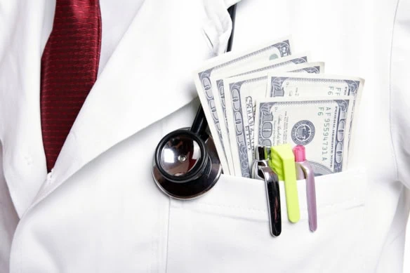 a doctor wears a lab coat that has pens and several hundred dollar bills in his pocket.