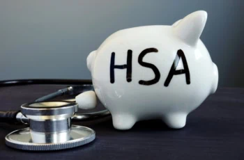 a piggy bank with the letters H S A on it sits next to a stethoscope.