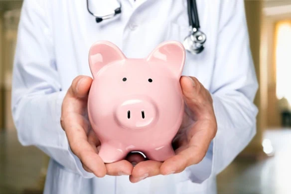 a doctor holds a piggy bank.
