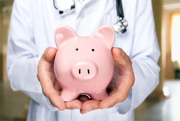 a doctor holds a piggy bank.